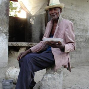 A man in a hat sitting on a rock promoting Community Feeding Programs.