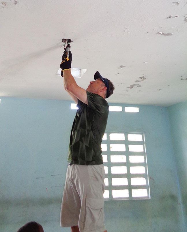 A man fixing the lighting fixture of a room