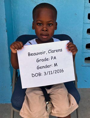 A young boy holding up a sign that reads beauvoir charters.