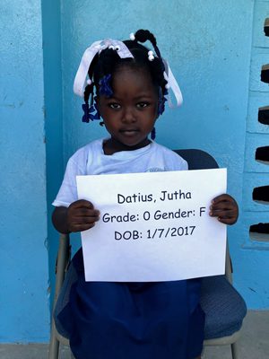 A little girl holding up a sign that says darrin julia grade o gender.
