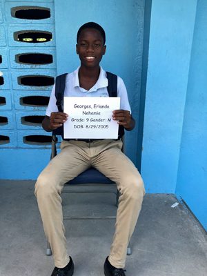 A boy sitting in a chair holding a sign.