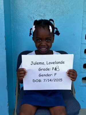 A little girl holding a sign that says grade pa gender f.
