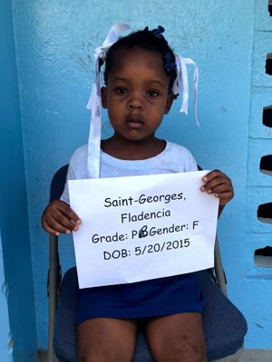 A little girl holding a sign that says saint george flint.