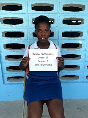 A girl sitting in a chair holding a sign.