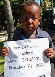 A boy holding up a sign that says pierre charles ferrens.