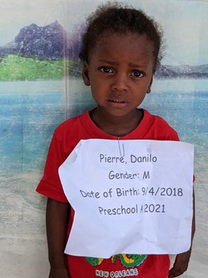A young boy holding a sign that says he is due to be born in 2021.