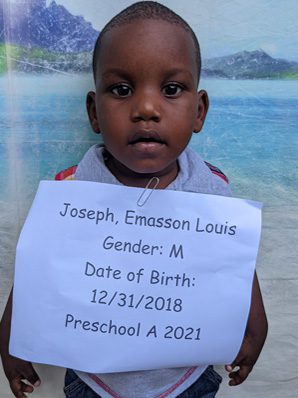 A young boy holding a sign that says joseph emmanuel louis.