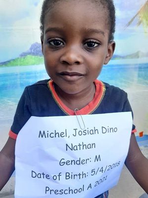 A young boy holding up a sign with the name michael dino.