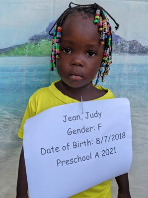 A little girl holding a sign that says jean judy gender.