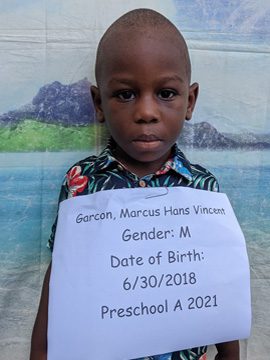 A young boy holding up a sign that says he was born in 2021.