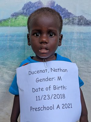 A young boy holding a sign that reads duncan gender m date of birth preschool a 2021.