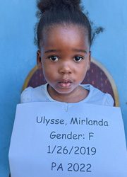 A young girl holding up a sign that says uysse, minanda, gender f.