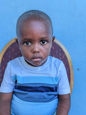 A young boy sitting on a chair looking at camera