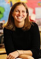 A smiling woman sitting in a classroom.